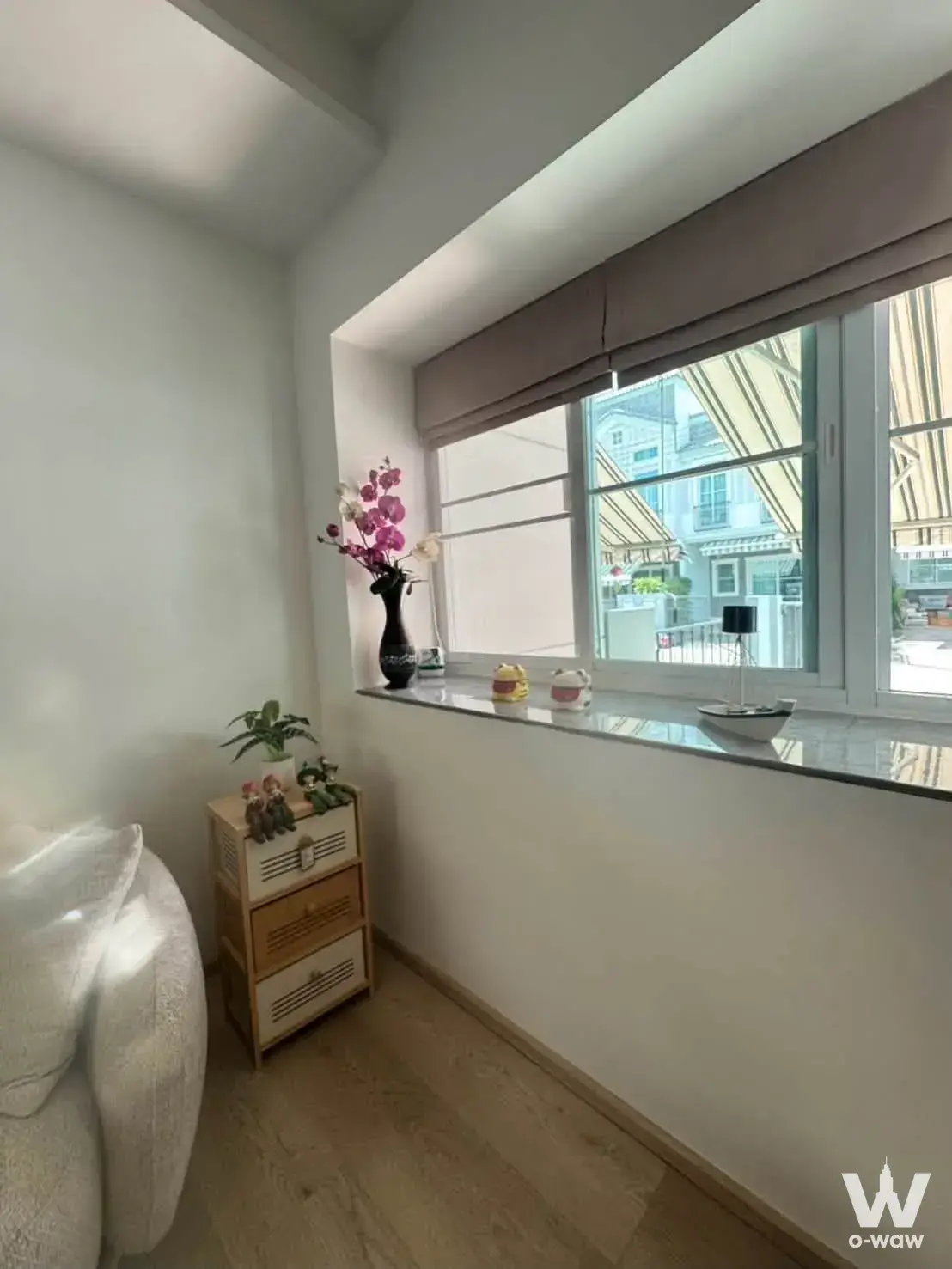 Indy 4 Bangna townhouse bedroom corner with orchids, light wood floors, and Roman shade window treatment