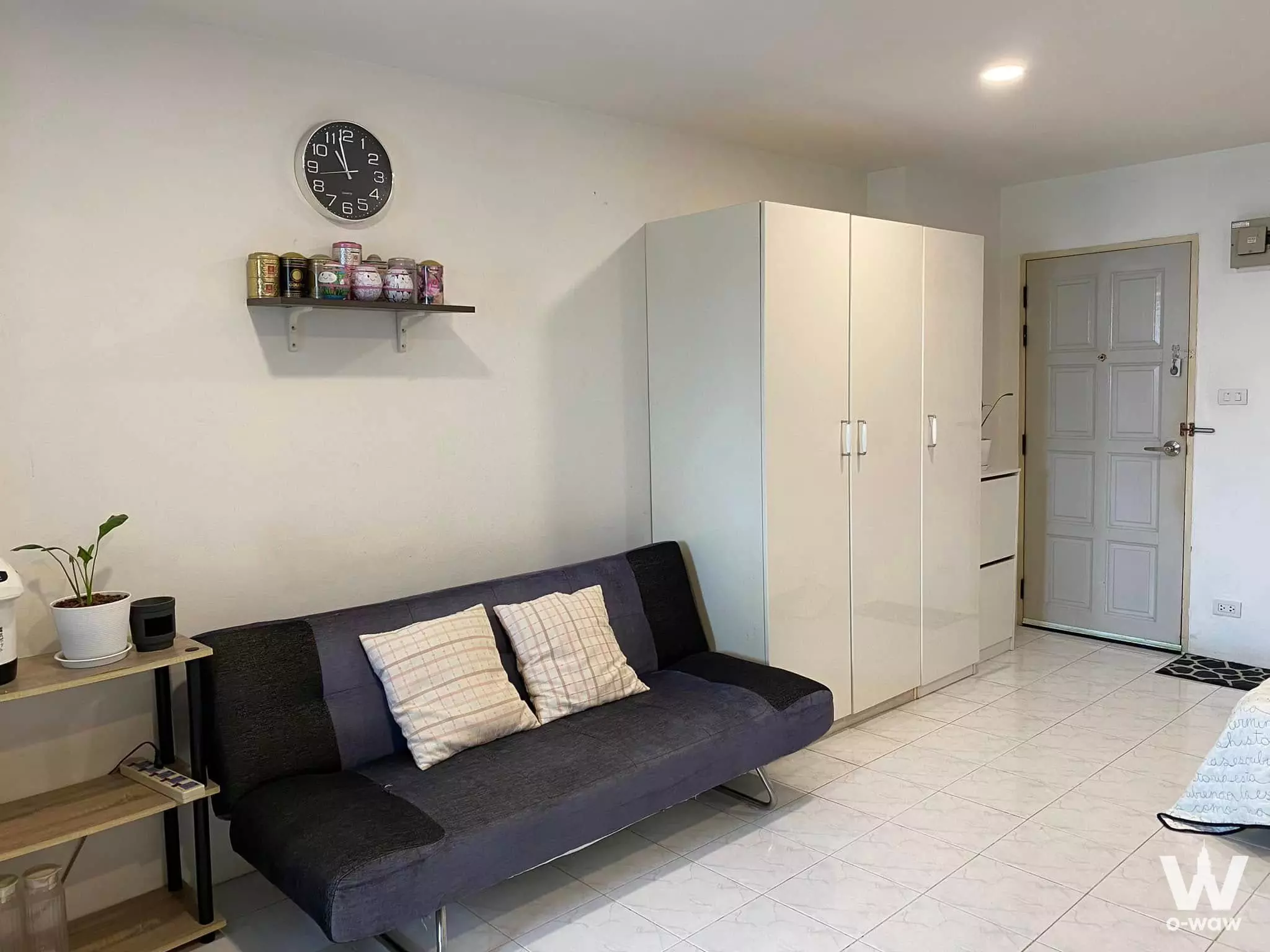 Cozy living room in a Royal Tower 3 sale listing featuring a grey sofa-bed and white tiled flooring