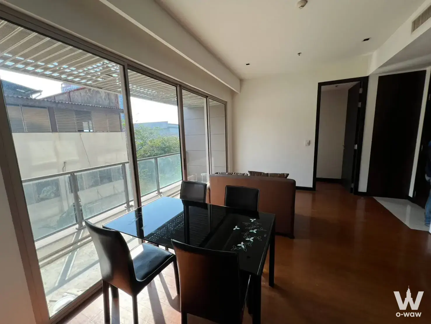 Dining space in a 2-bed condo for sale at The Lofts Yennakart with dark wood floors and sliding glass balcony doors
