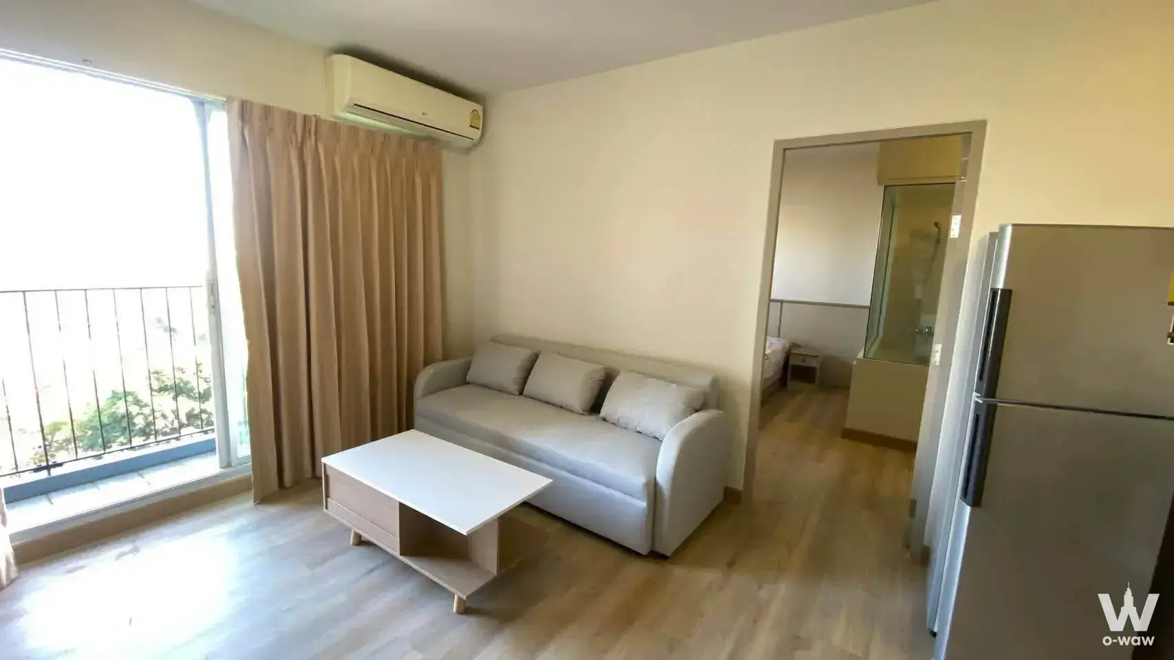Bright open-plan living room in Chapter One Ratburana with floor-to-ceiling glass doors and light wood floors