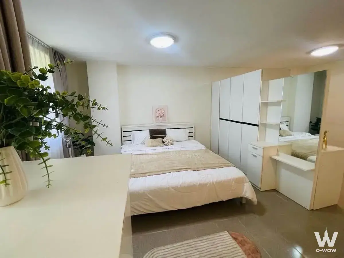 Modern bedroom in The Parkland Bangna condo with white slatted headboard, built-in wardrobe, and vanity mirror
