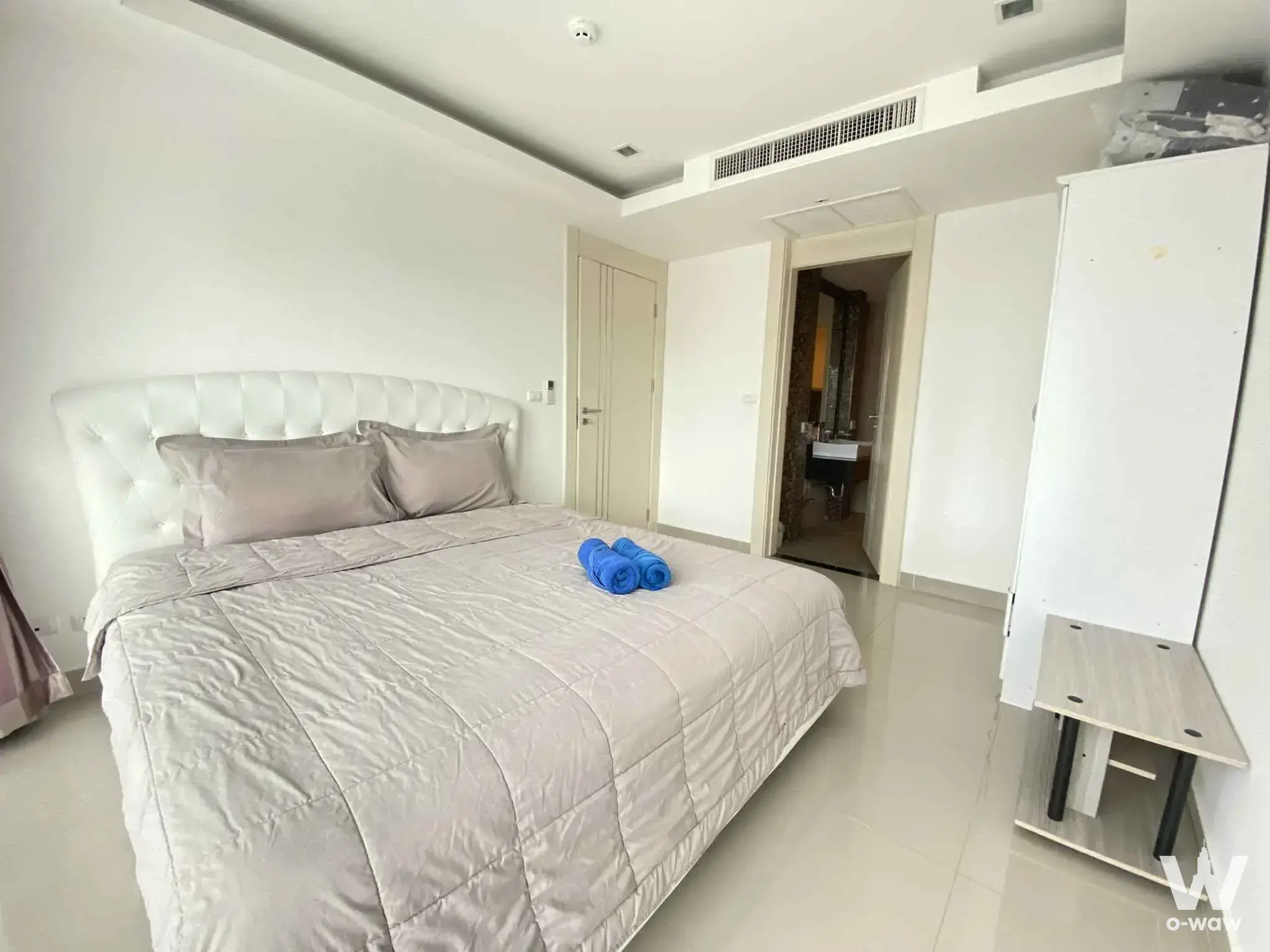 Bedroom in Cosy Beach View condo with tufted leather headboard and open bathroom doorway