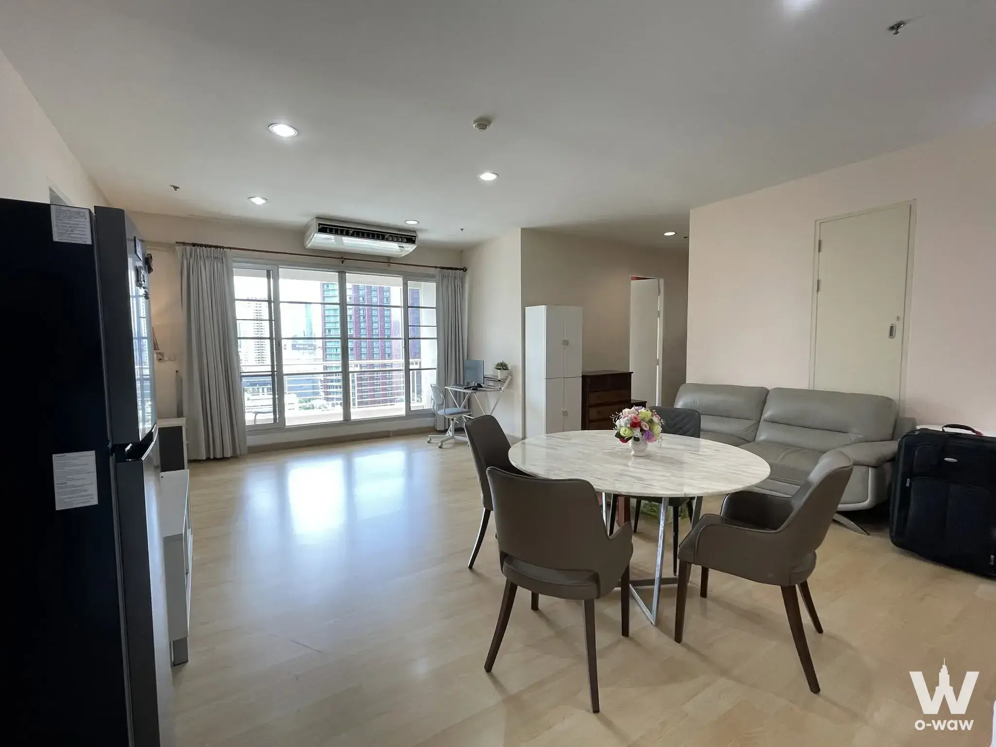 Open-plan living area in Baan Klang Krung Siam-Pathum Wan with marble dining table and high-rise city view