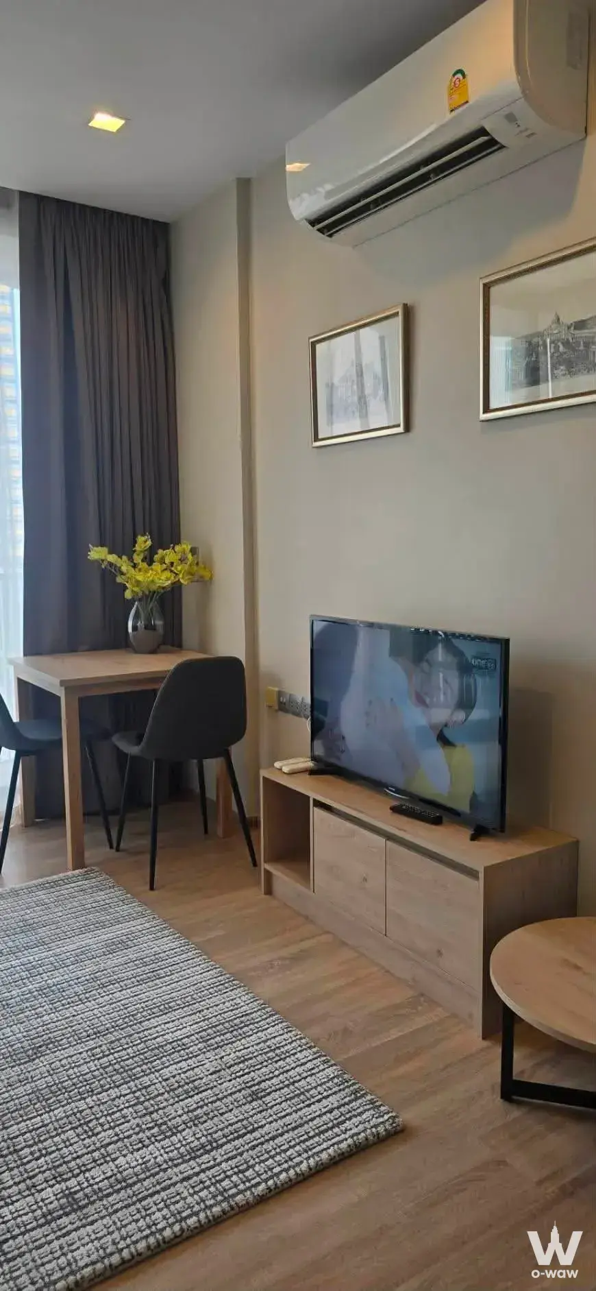 Open-plan living and dining nook in Kawa Haus 1-bed condo featuring light oak media console and round coffee table