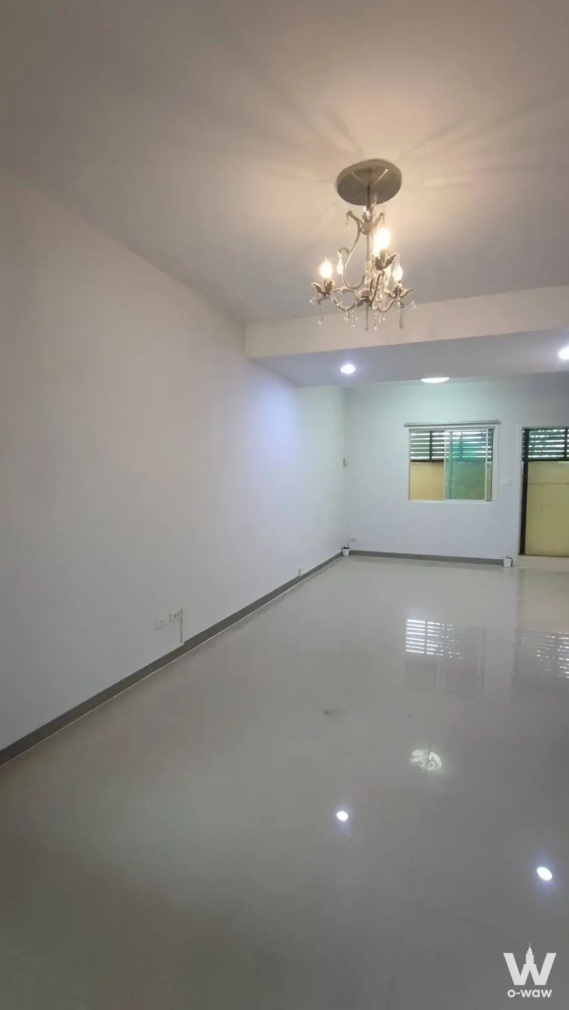 Empty living room in a 3-bed townhouse for rent at Pruksa Ville Bangna featuring glossy grey tiles and a crystal chandelier