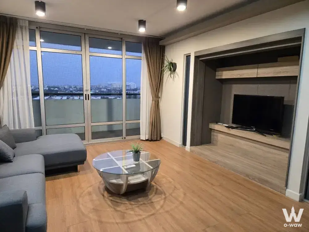 Modern living room in The Riviera Ocean Drive condo with grey sectional sofa facing city skyline at dusk