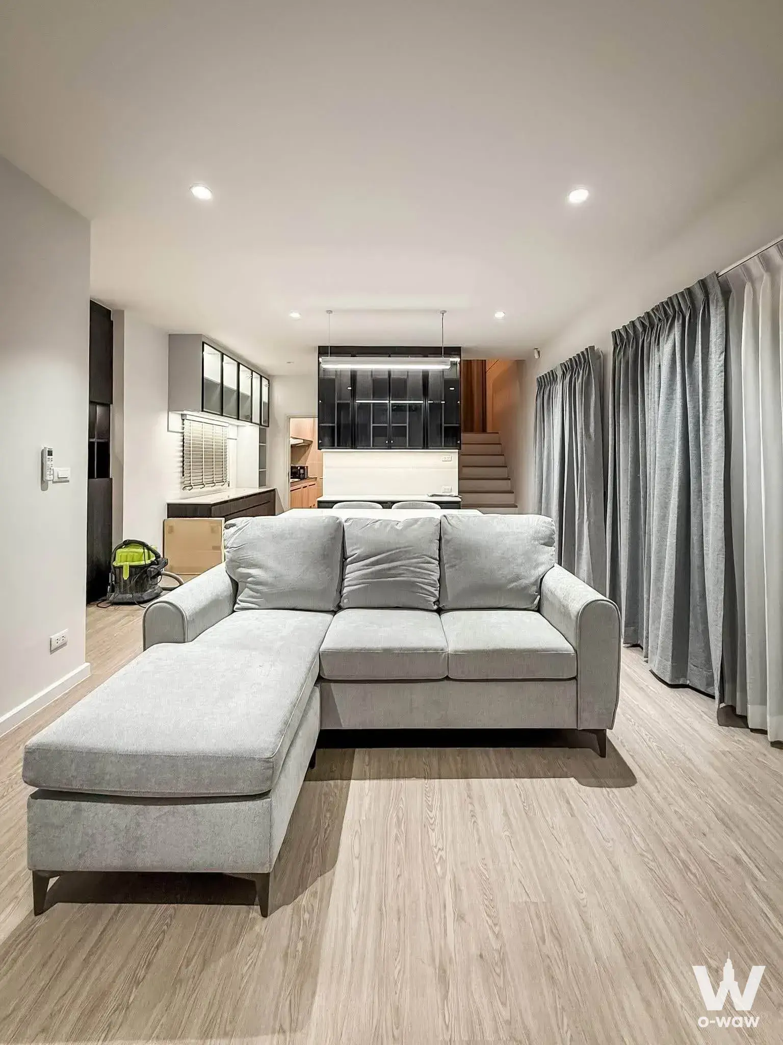 Open-plan living room in a 4-bed Saransiri house featuring light oak floors and a view of the open kitchen