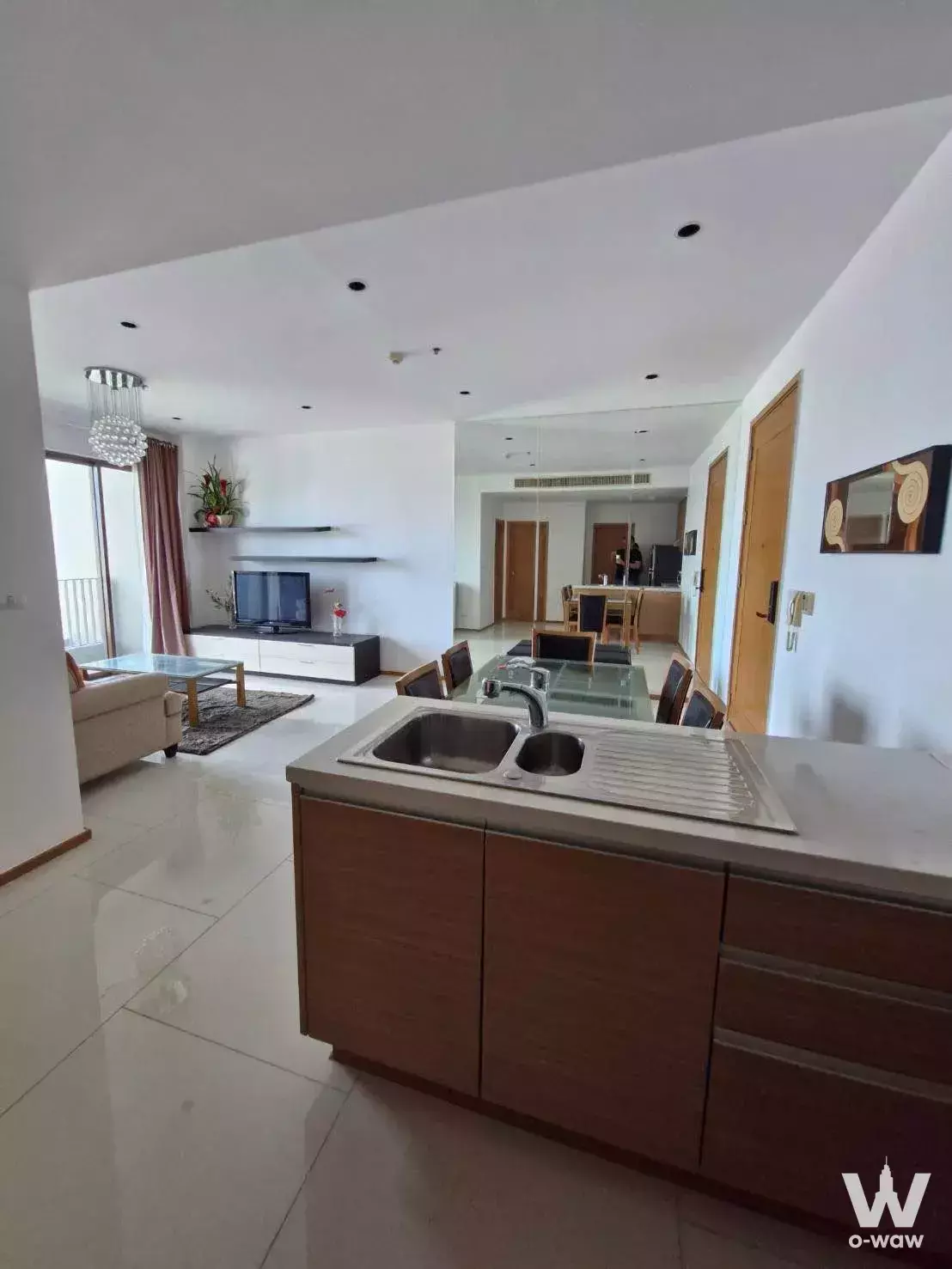 The Emporio Place furnished living room with dining table, sofa, and balcony access