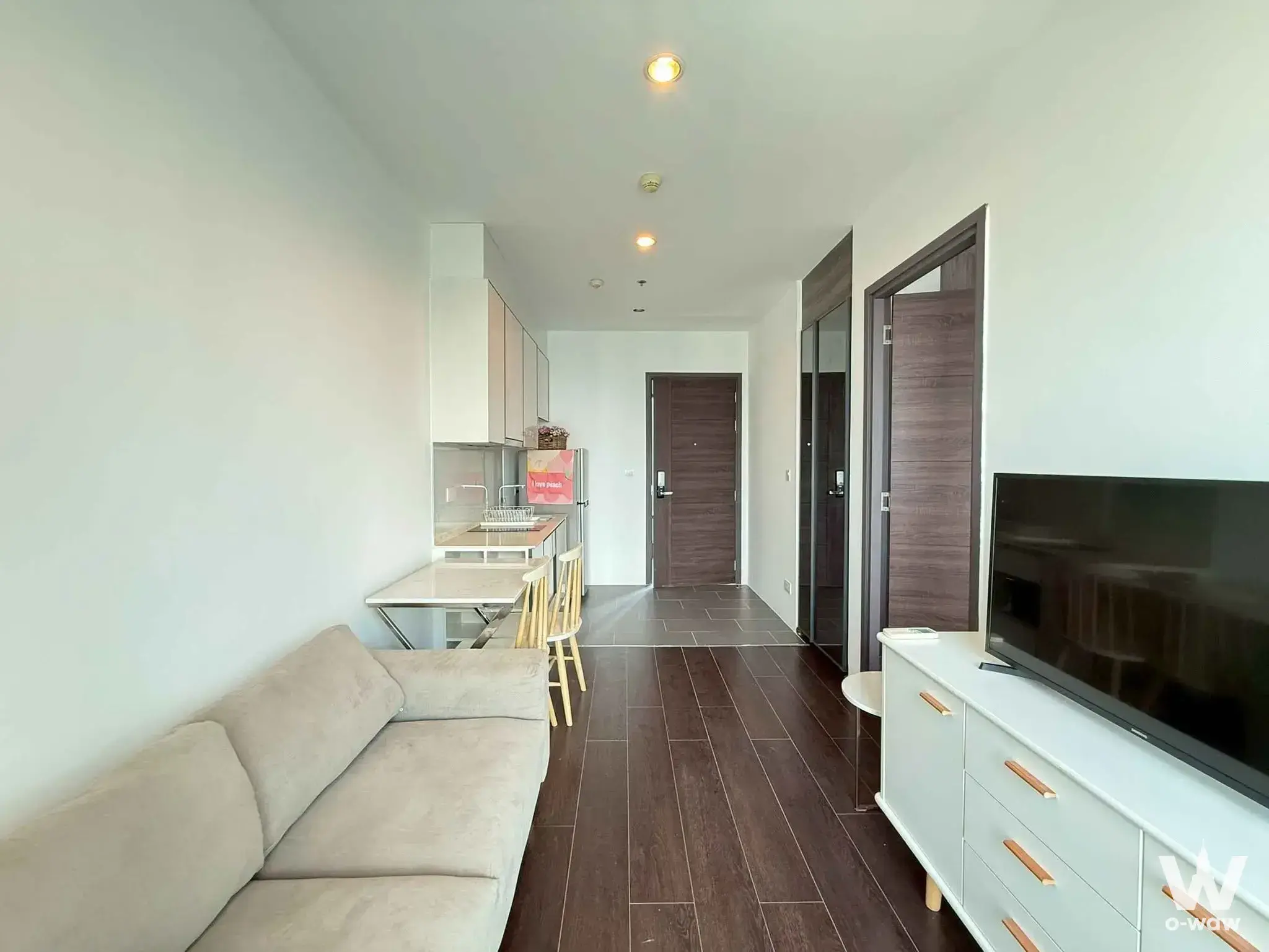 Open-plan living area with compact kitchenette in this 1-bed condo for rent at C Ekkamai Condominium