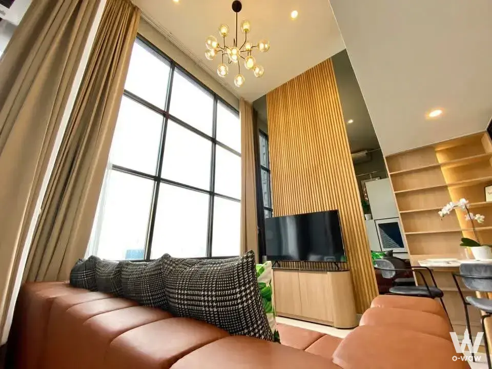 Living room in KnightsBridge Prime Sathon condo with terracotta sectional sofa and wood slat accent wall