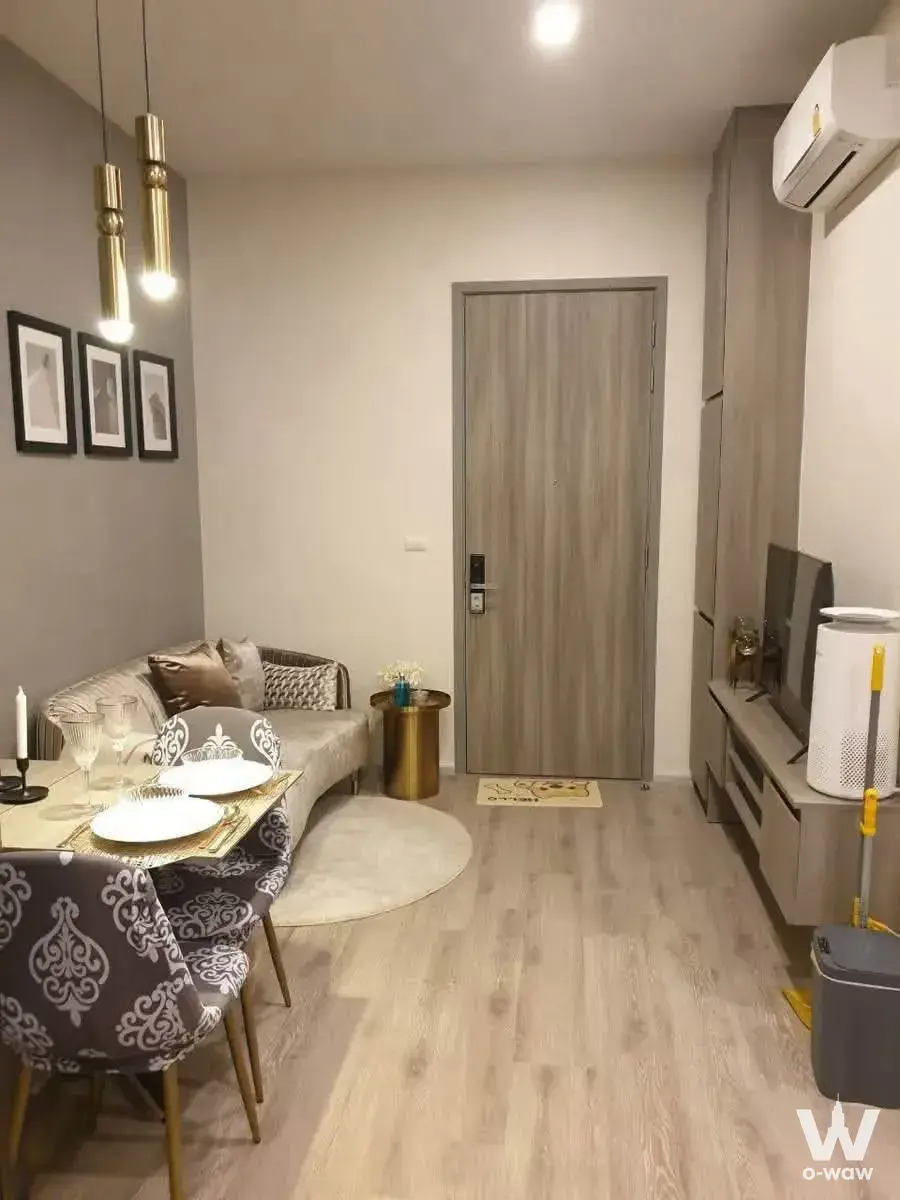 Open-plan living and dining area in KnightsBridge Prime Ratchayothin condo with gold accents and grey accent wall