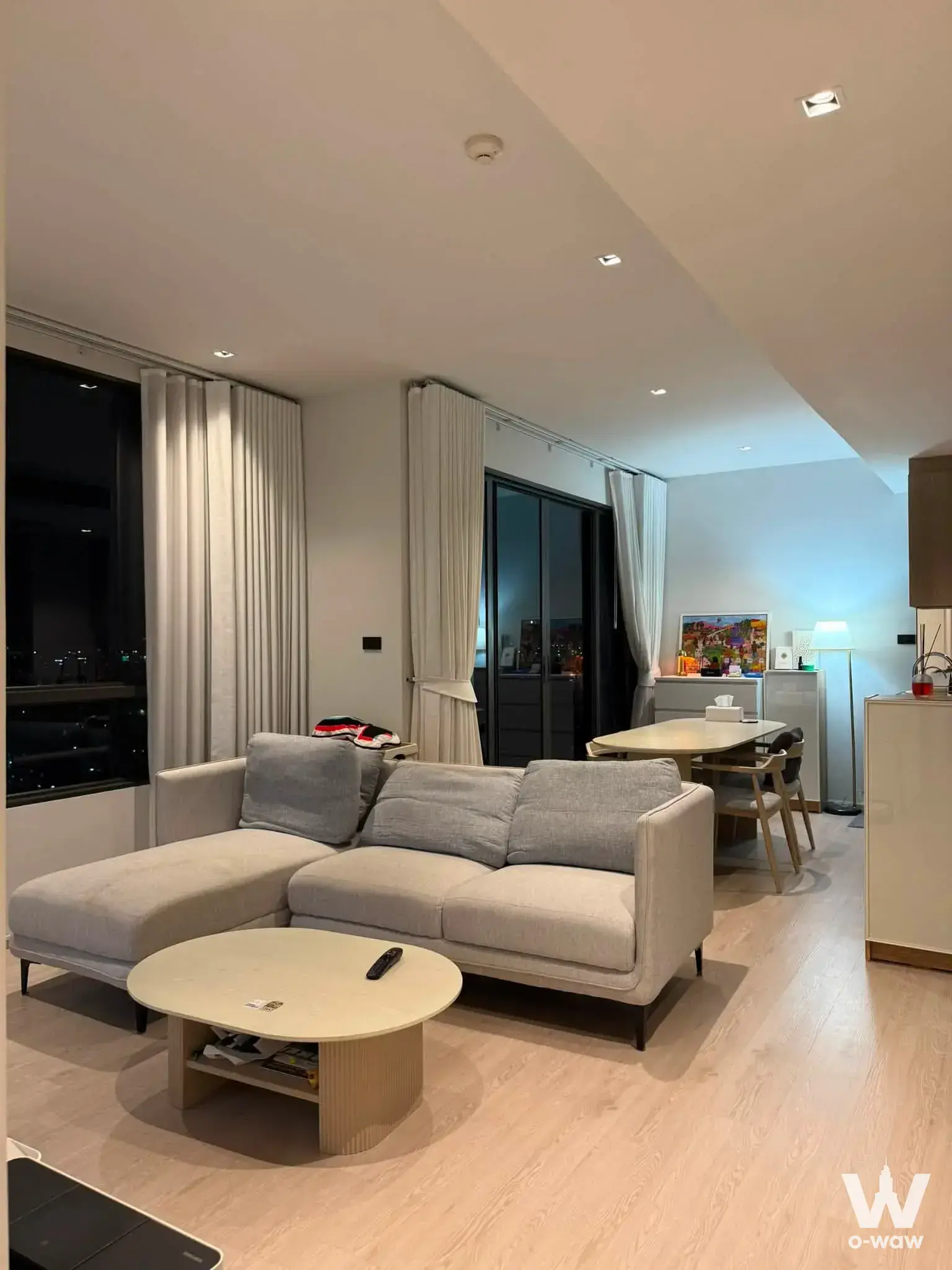 Beige sectional sofa and dining set in a Reference Sathorn-Wongwianyai living room with floor-to-ceiling night views
