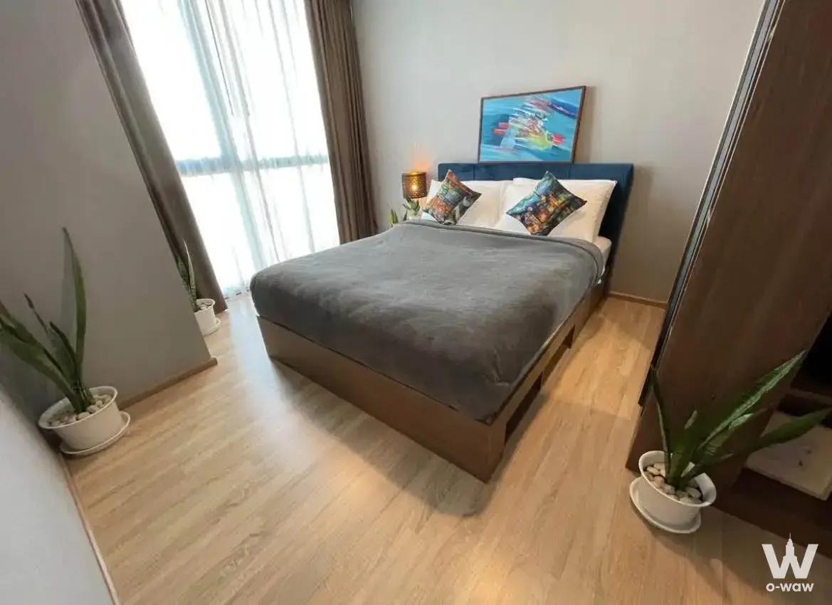 Bright bedroom in a Taka Haus 1-bed condo with queen bed and blue headboard