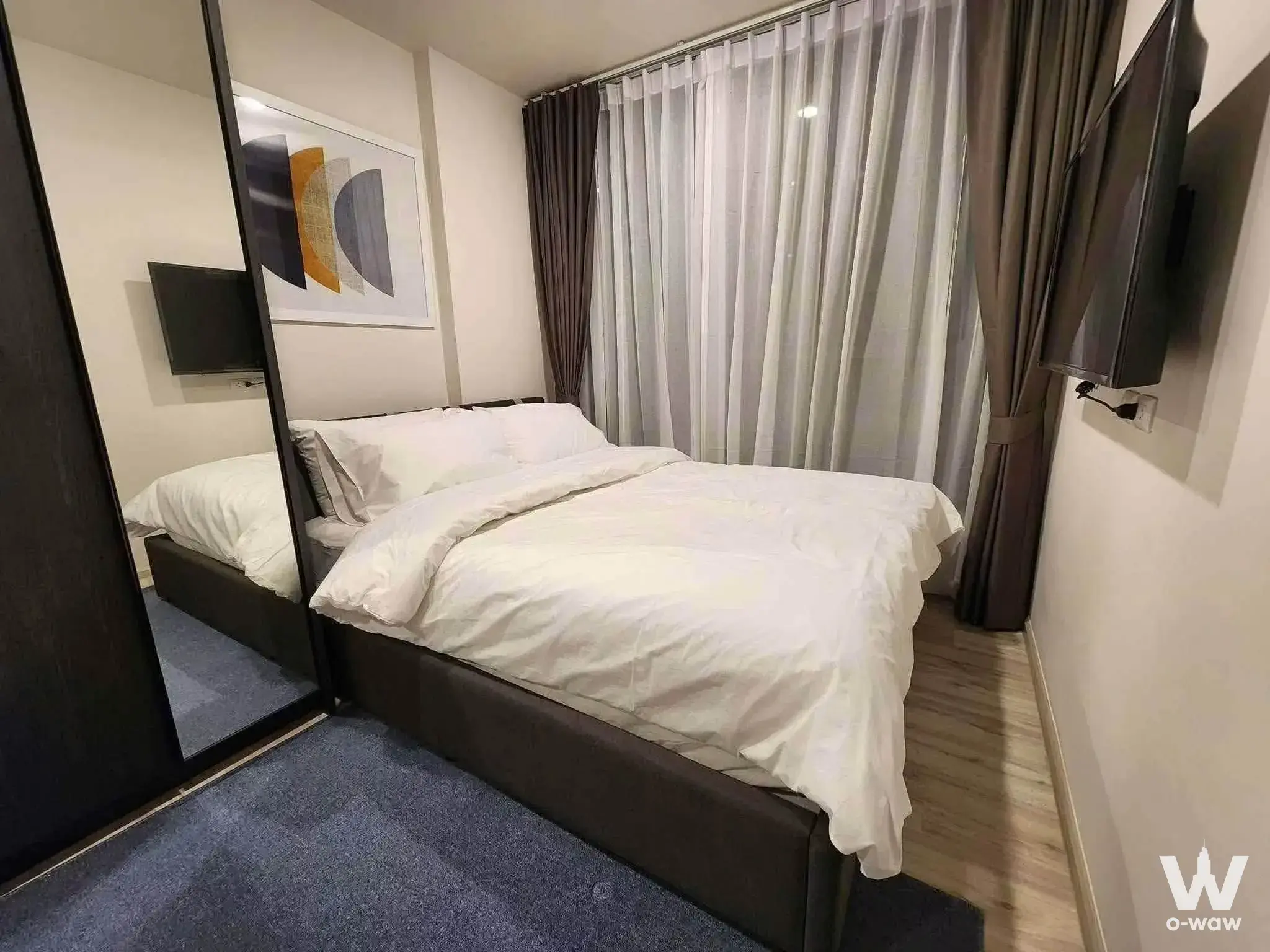 Furnished bedroom in a 1-bed condo for rent at XT Huai Khwang featuring a queen bed, mirrored wardrobe, and city-view window