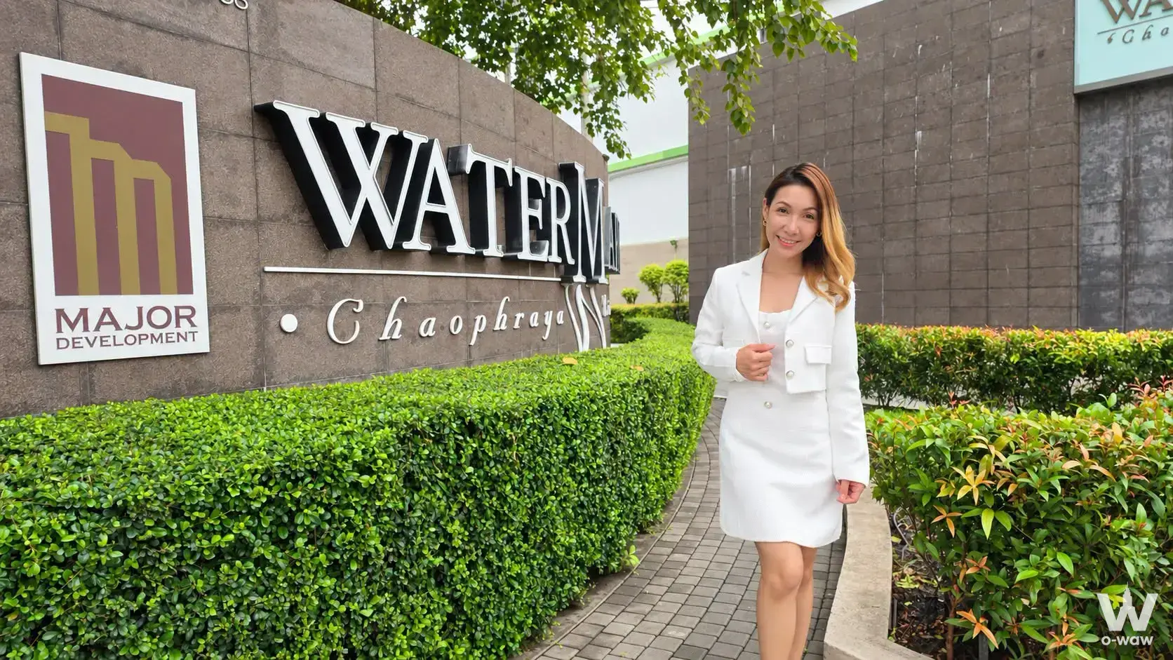 The entrance of a Watermark Chao Phraya 3-bed condo for sale shows signage and a woman in a white suit