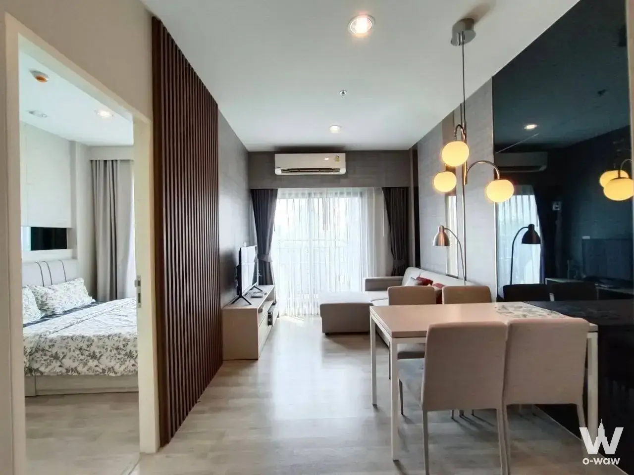 Modern open-plan condo featuring dining area with pendant lights, wood-slat partition, and living zone in a 2-bed rental in