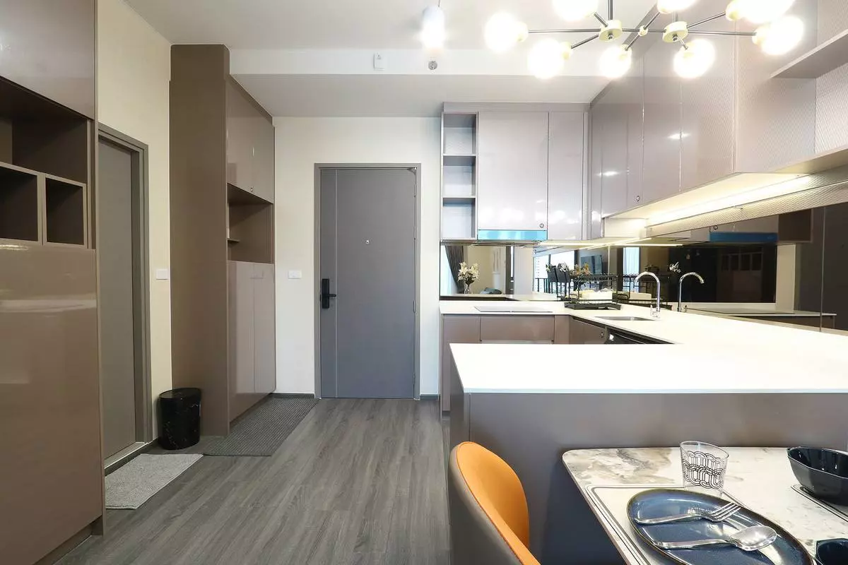 Open-plan kitchen in an IdeO Sukhumvit Rama 4 sale listing featuring taupe cabinets and quartz island