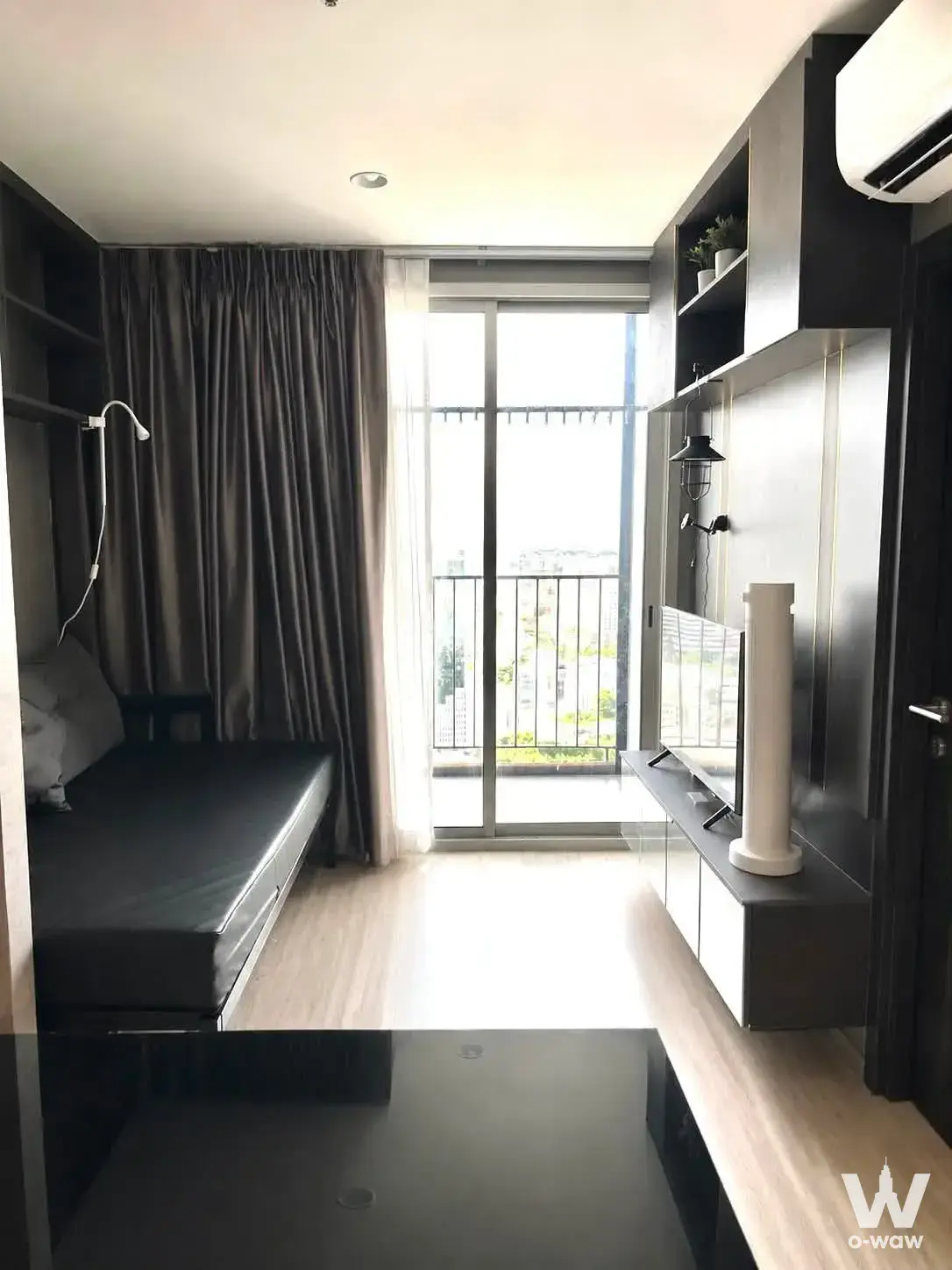 Compact living space in XT Huai Khwang condo featuring a Murphy bed, dark wood unit, and balcony access