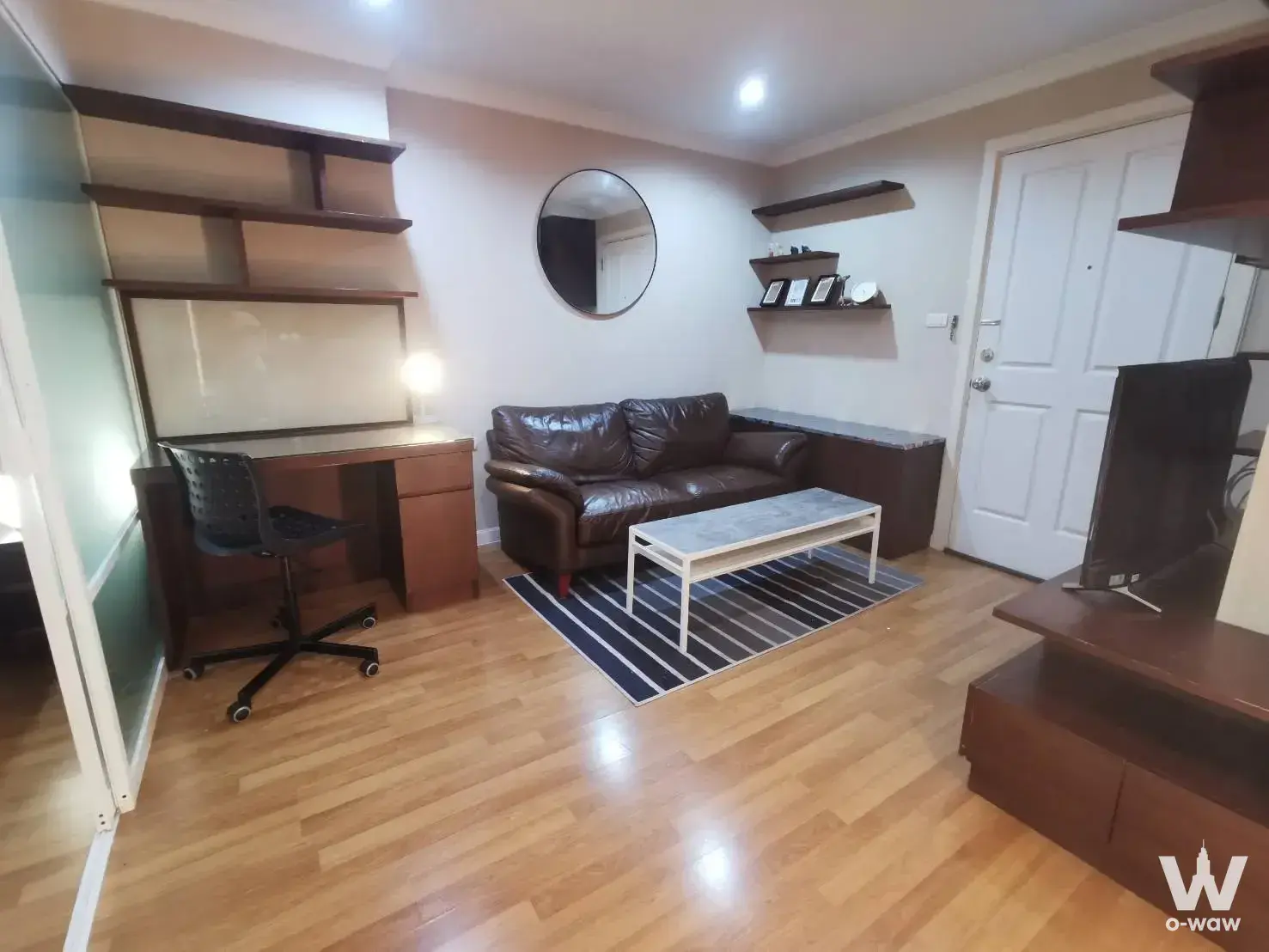 Furnished living and study combo in Lumpini Place Rama 9 rental with honey wood floors and leather sofa