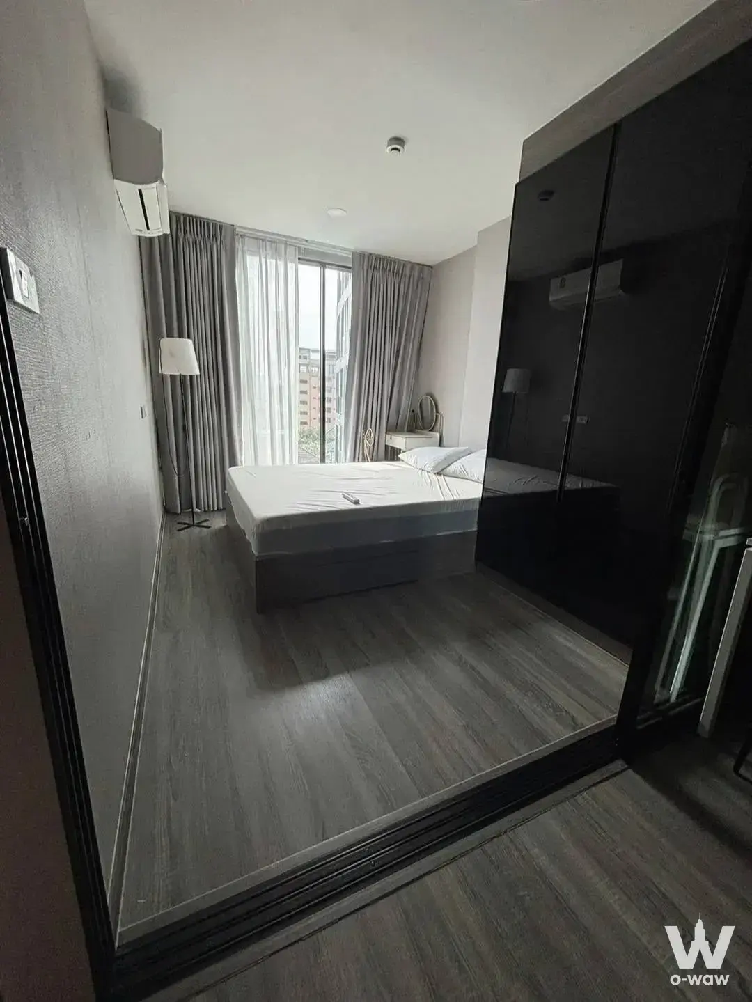 Bedroom in The Origin Ladprao 15 1-bed condo with dark wood floors and a mirrored wardrobe