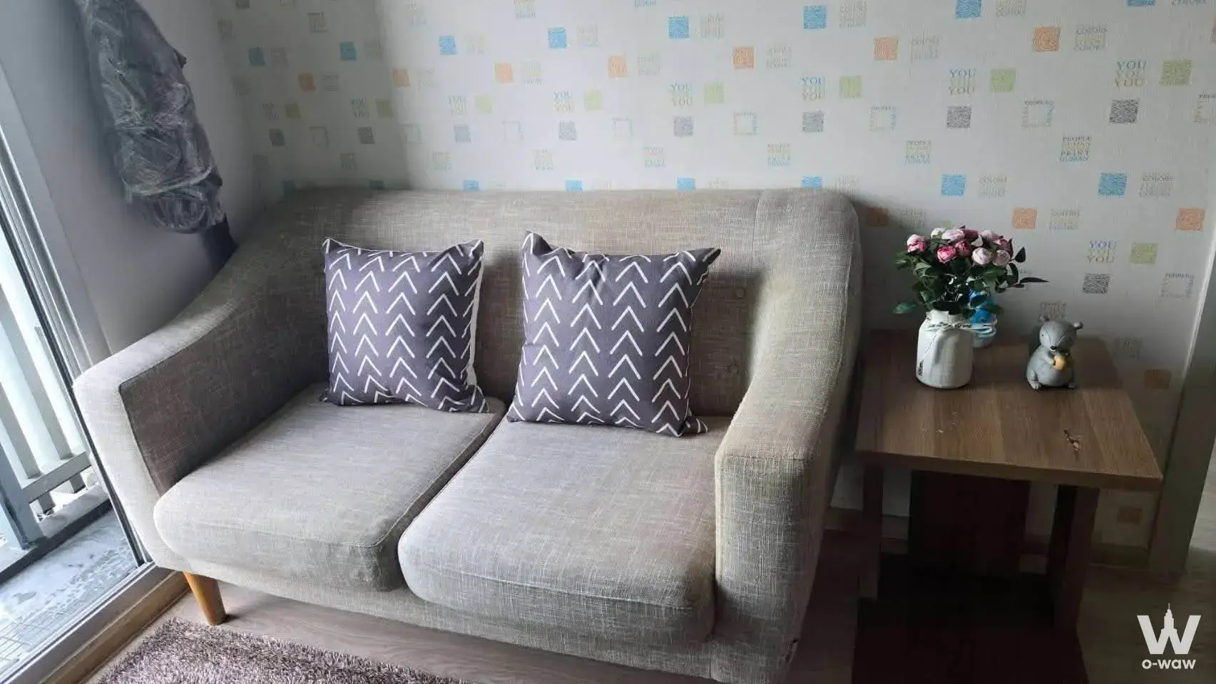 Cozy 1-bed condo living room in Noble Revolve Ratchada 2 with grey sofa and geometric wallpaper