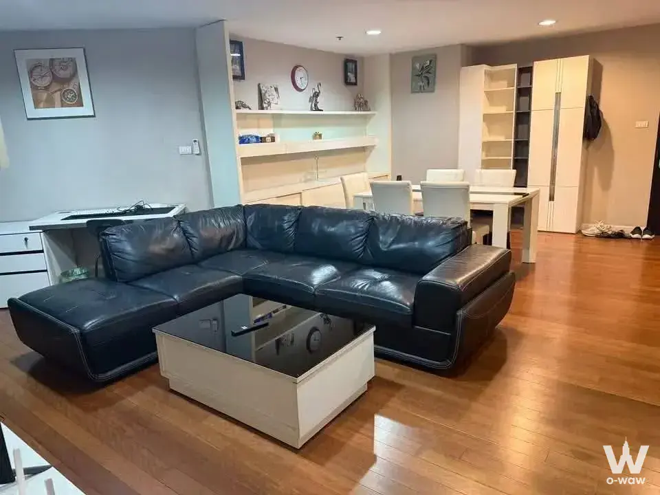 Furnished living space in Belle Grand Rama 9 condo with black sofa and built-in white shelving