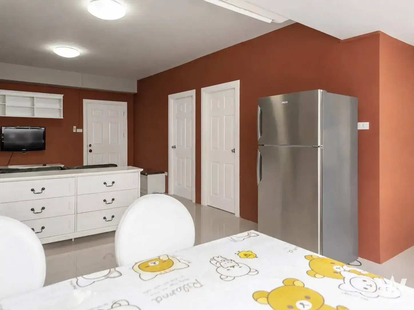 Open-plan living area with terracotta orange accent walls in a 2-bed Keerasap Mansion Ville condo