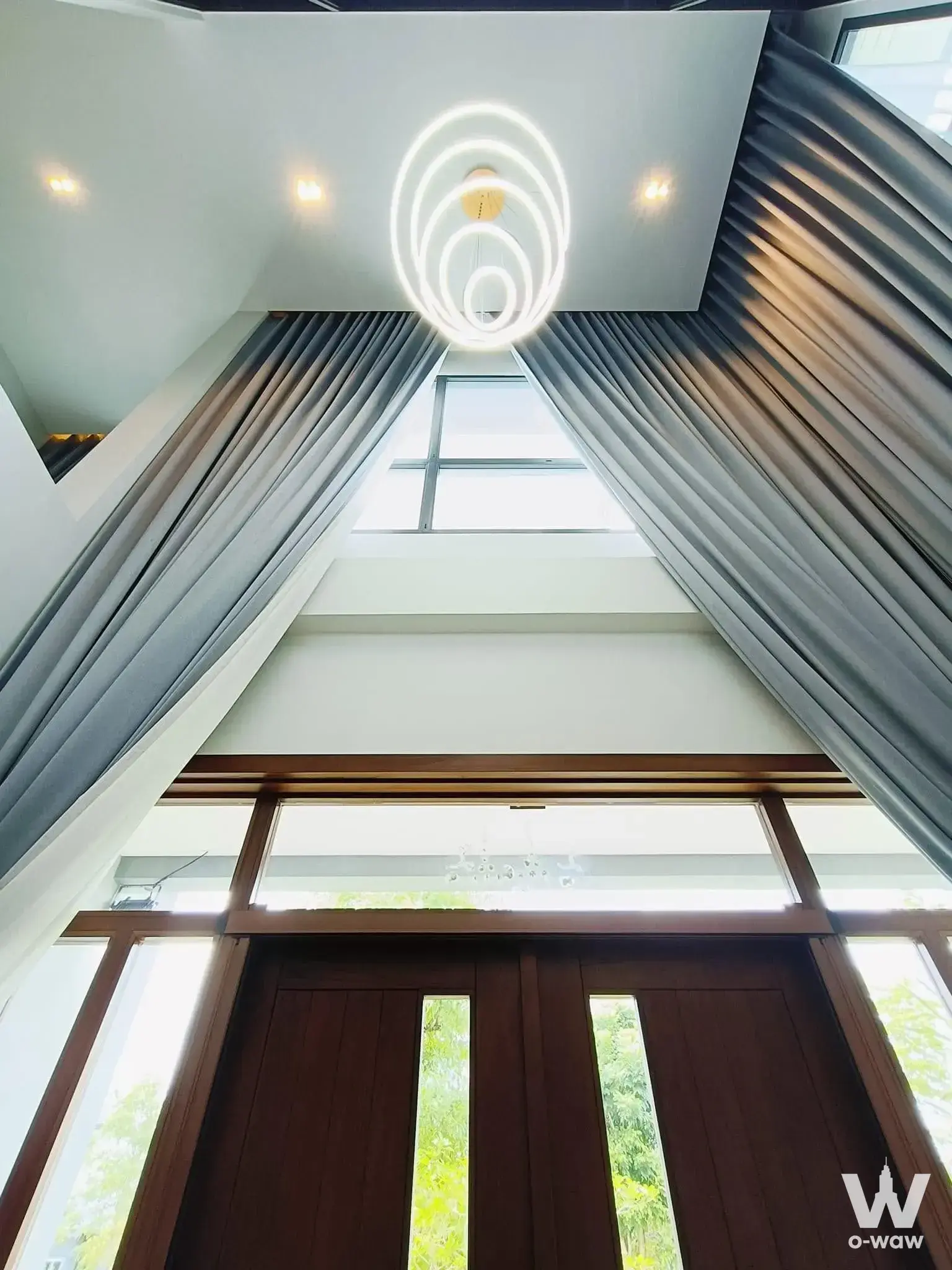 Double-height foyer with gold chandelier and dark wood doors in The City Watcharapol 4-bed condo