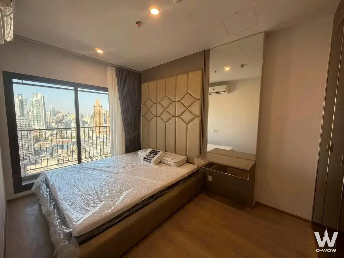 Queen bed with tufted headboard and floor-to-ceiling window in this Asoke condo bedroom
