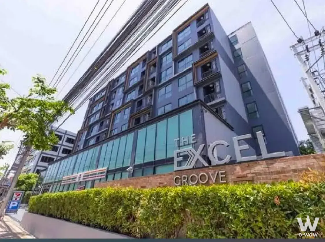 Low-angle exterior view of The Excel Groove building featuring dark facade panels and large silver signage
