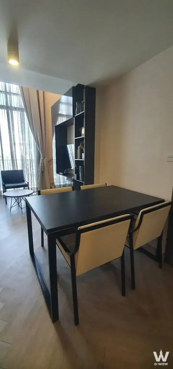 Maestro 02 Ruamrudee 3-bed condo dining area featuring black table, shelving, and minimalist decor