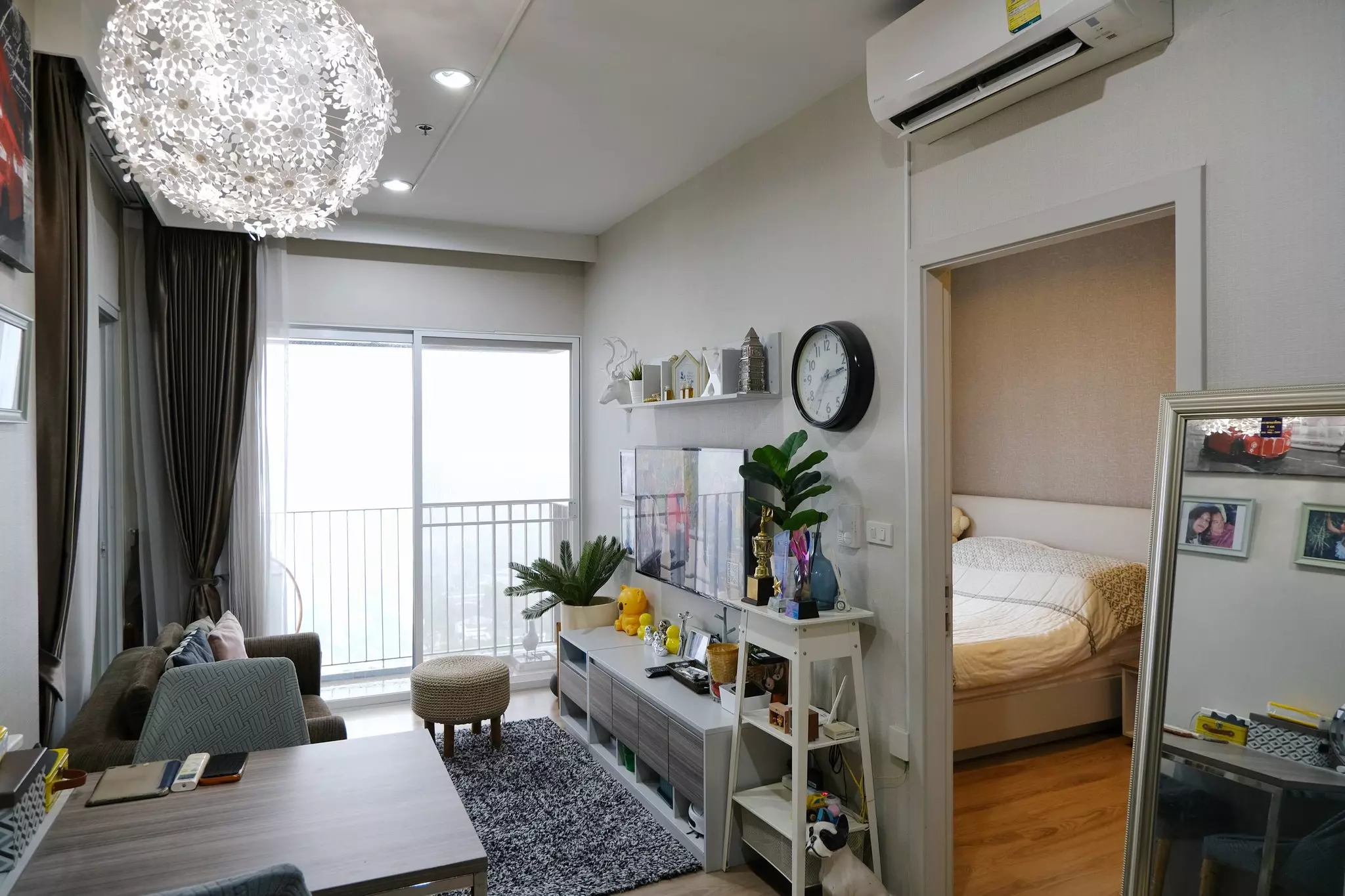 Bright 1-bed condo living room in Amber Condominium with sofa, chandelier, and balcony access