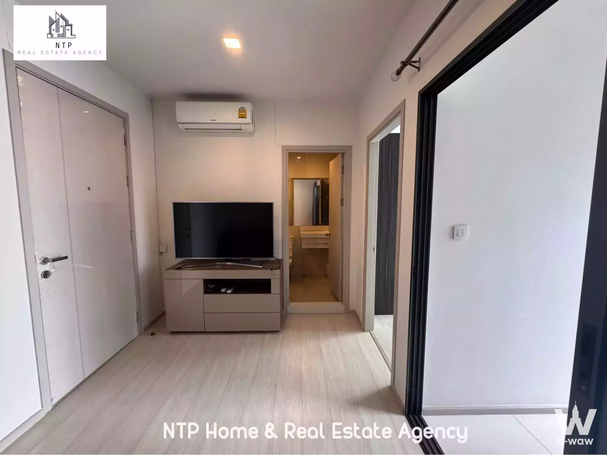 Life Sukhumvit 48 living room with light wood floors, built-in wardrobe, and open bathroom doorway