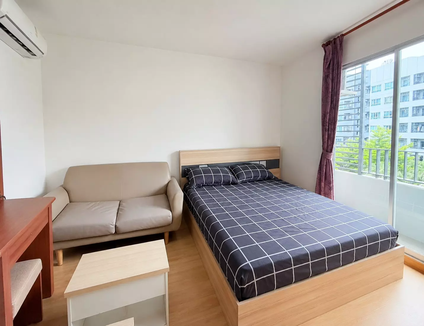 Queen bed with dark grey bedding in Elio Del Ray condo next to a sliding glass door leading to a balcony view