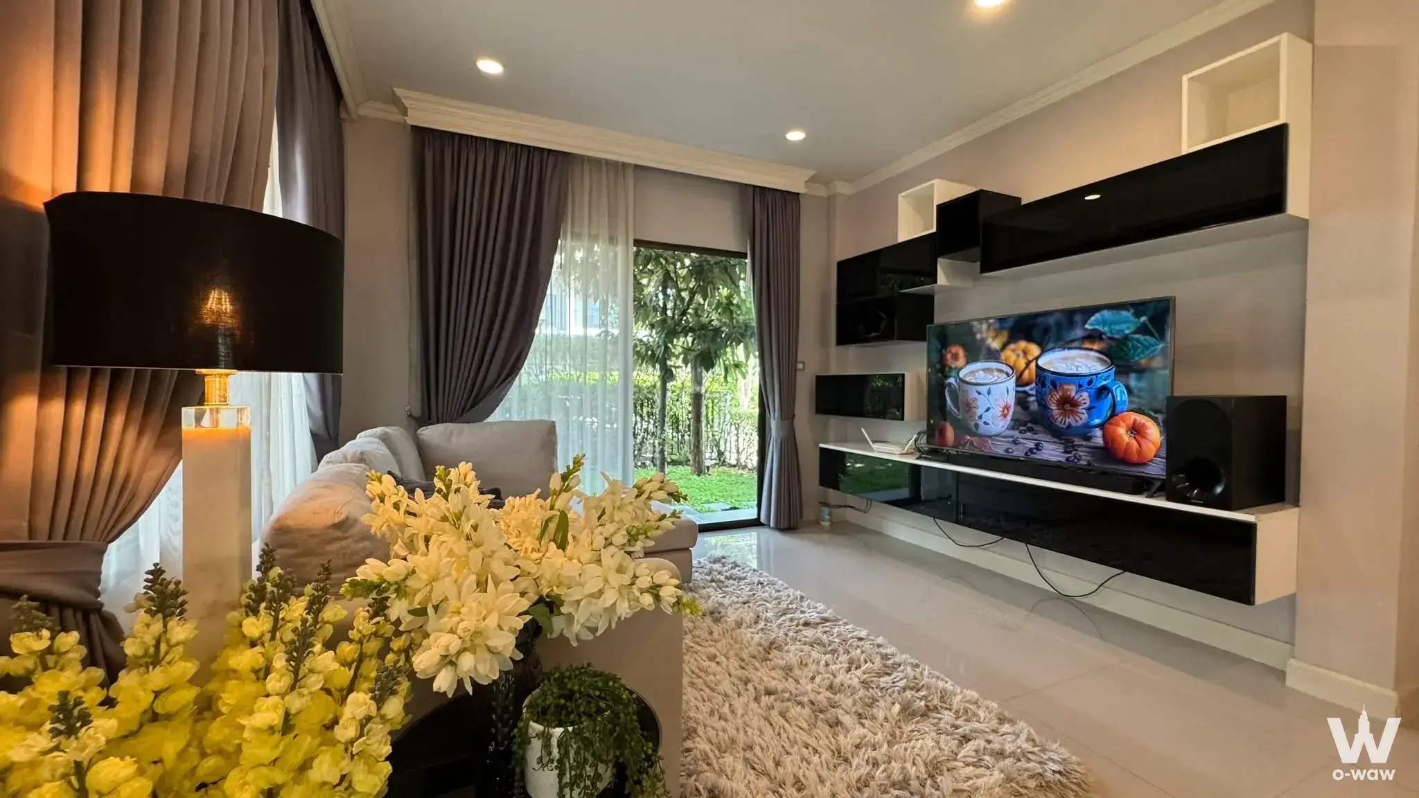 Luxury 5-bed condo for sale in The City Ramintra-Wongwaen 2 showing a furnished living room with black floating shelves and