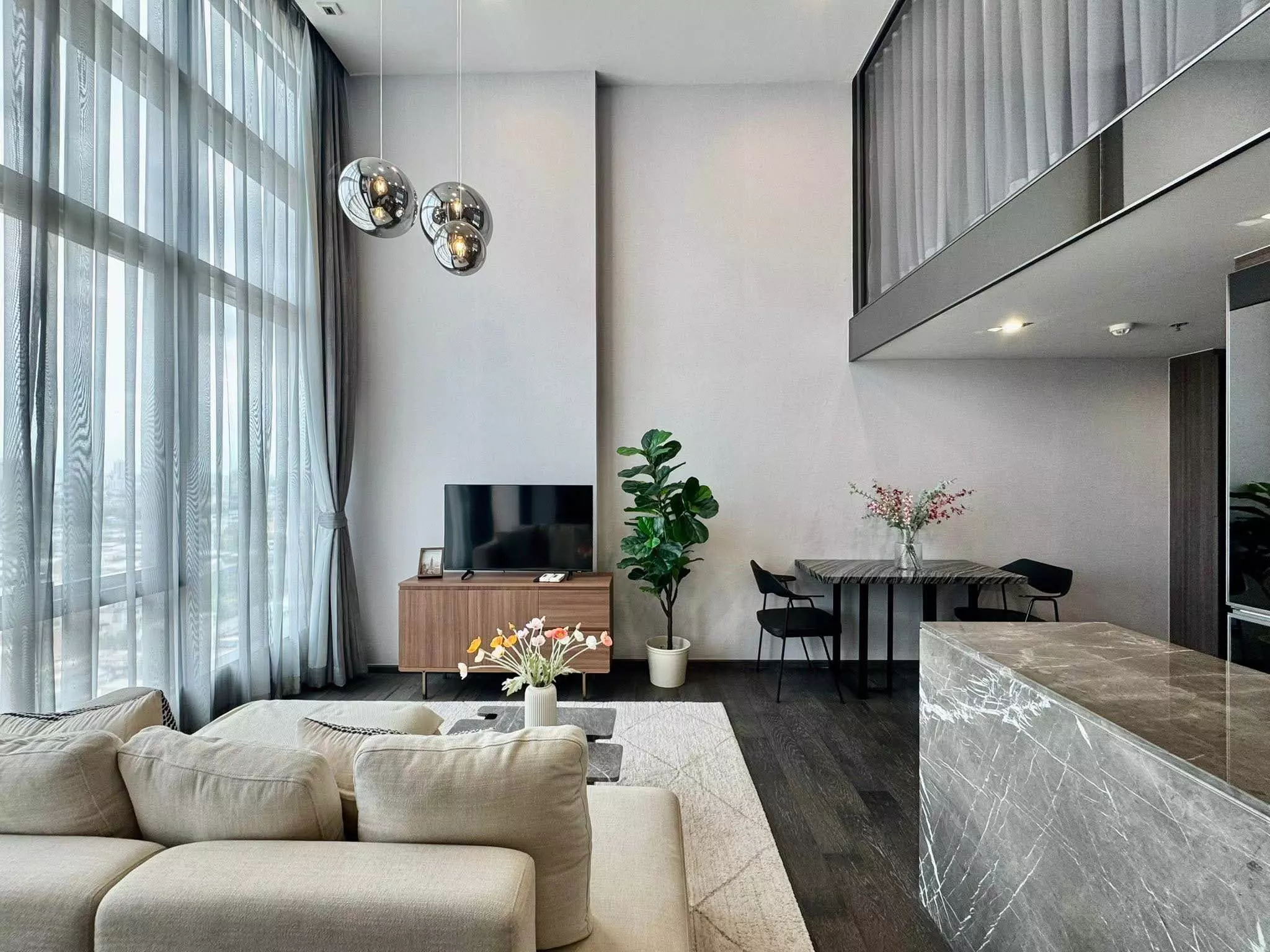 Duplex loft style 1-bed condo for rent in CONNER Ratchathewi with high ceilings, marble island, and mezzanine level visible