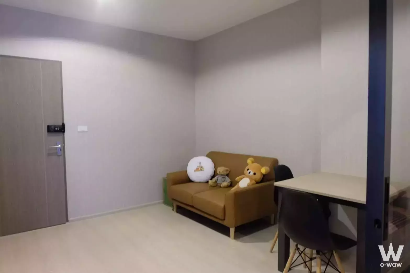 Studio unit for rent in IDEO Sukhumvit 115 with tan sofa, Eames-style chairs, and smart lock entry
