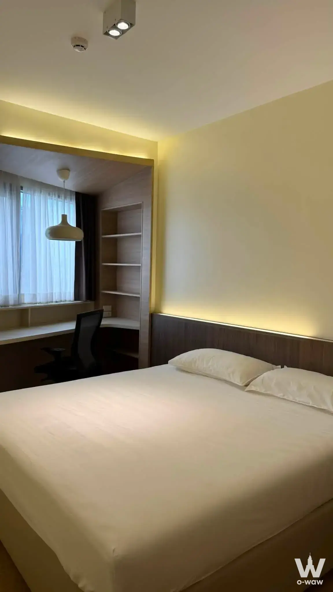 Modern bedroom in a Triple Y Residence 2-bed condo with a queen bed, LED headboard lighting, and a built-in window bay study