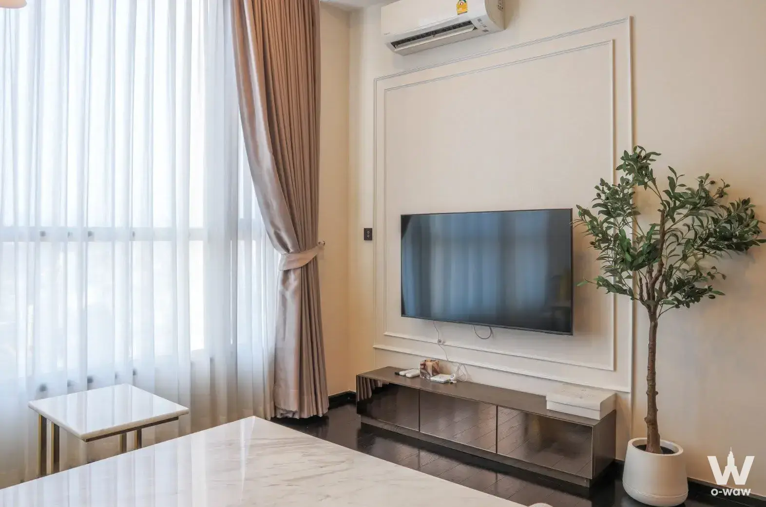 Spacious living room with floor-to-ceiling windows, dark wood floors, and marble table in a Park Origin Thonglor condo