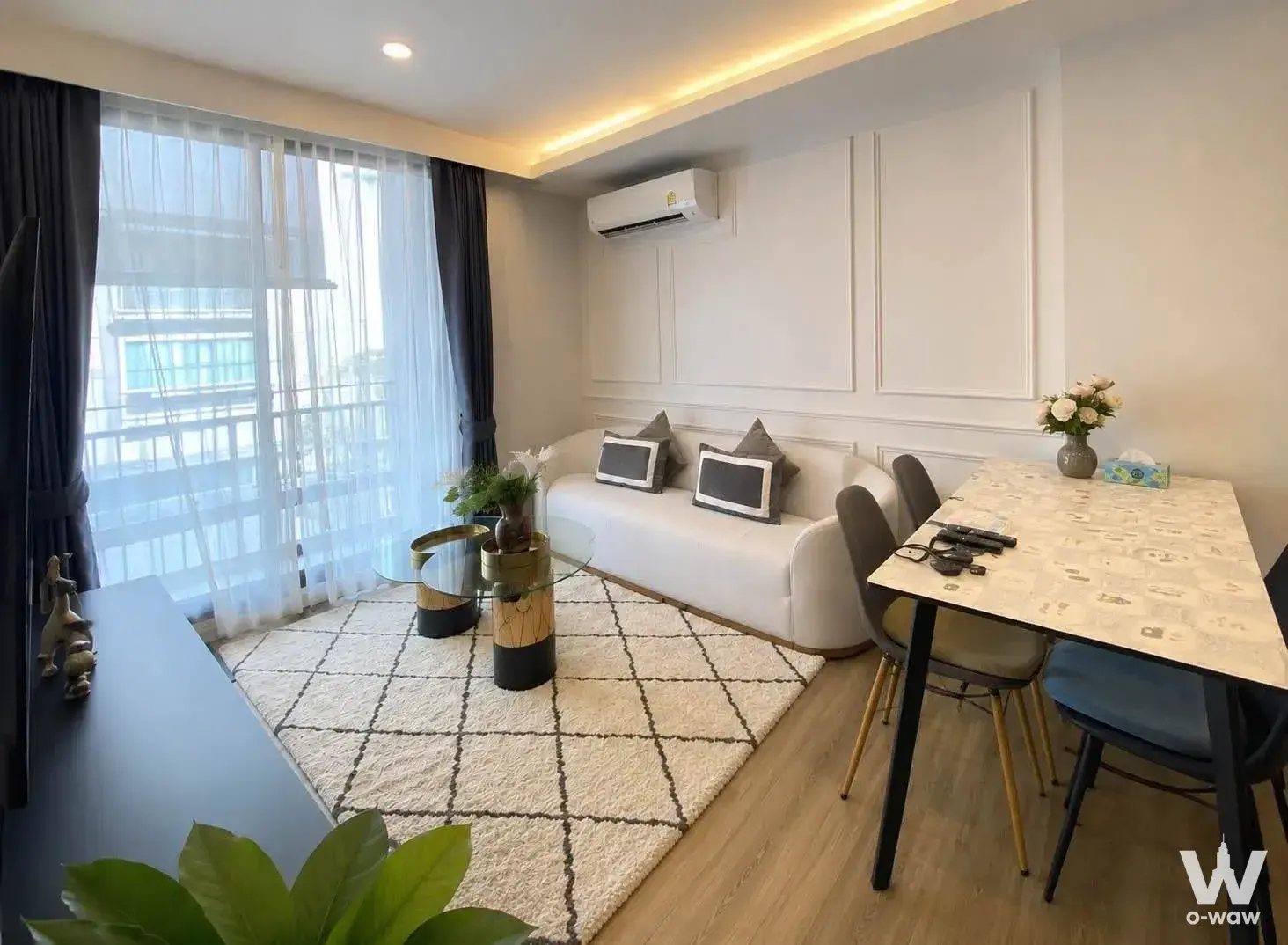 The living and dining room of a 2-bed condo for rent in Very Lasalle has floor-to-ceiling windows and a white sofa
