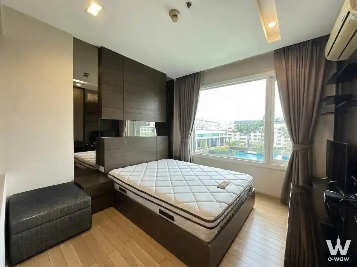 Master bedroom in a 2-bed Siri condo with dark wood headboard and pool view