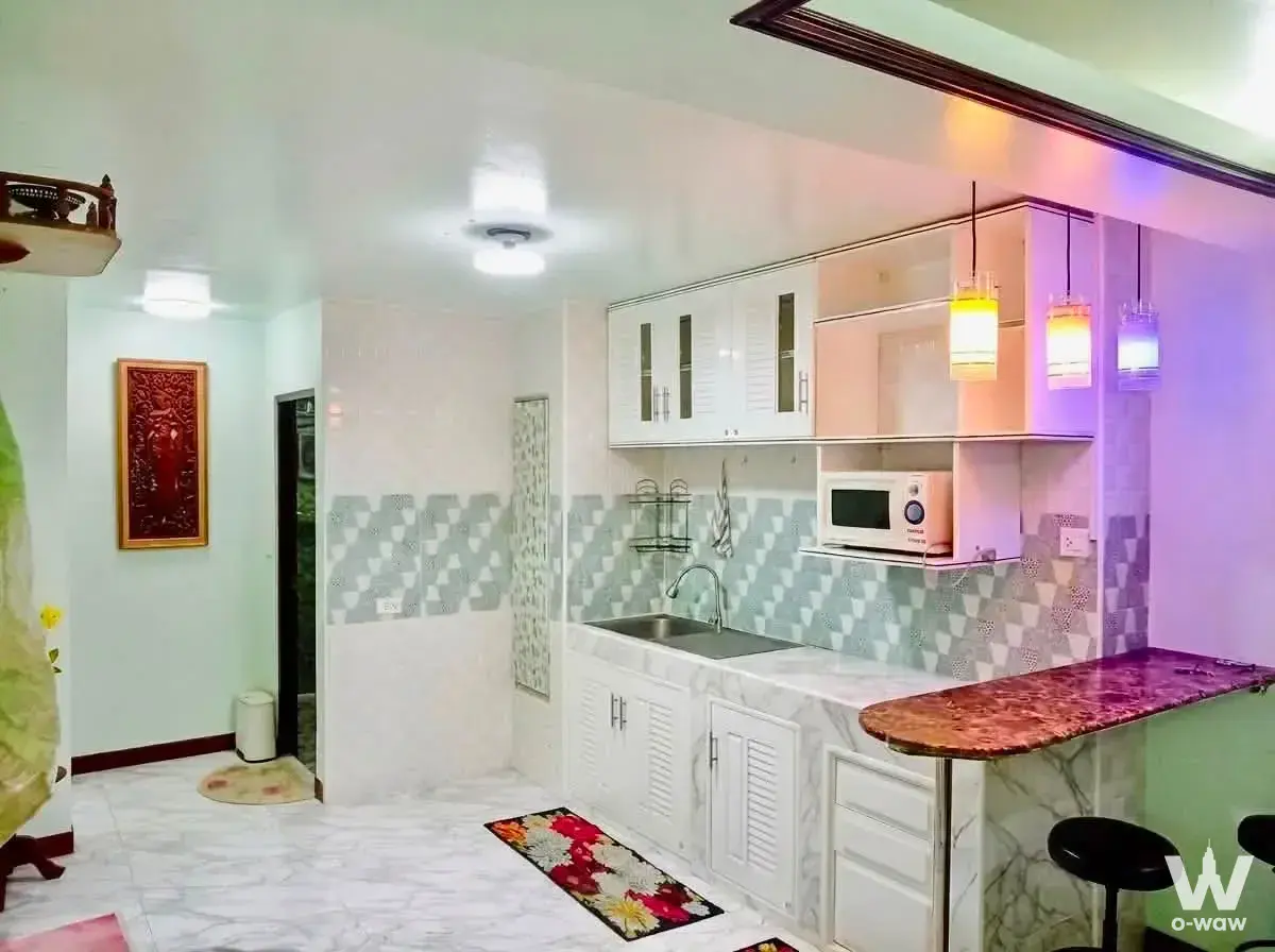 Kitchen in Premier Condominium with marble countertops, bar stools, and colorful pendant lights