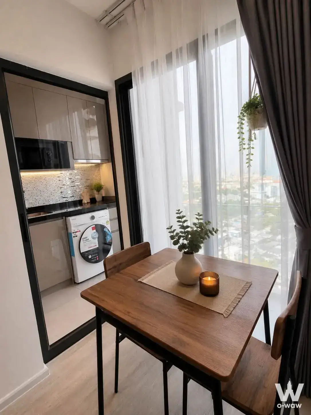 Dining area in THE LINE Wongsawang 0-bed condo with walnut table, window view, and kitchenette