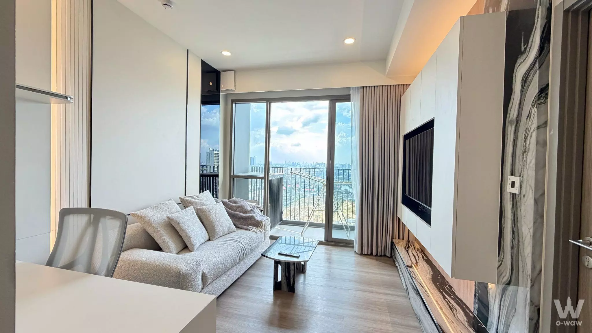 Living room with marble accent wall and balcony view in Whizdom the Forestia Petopia