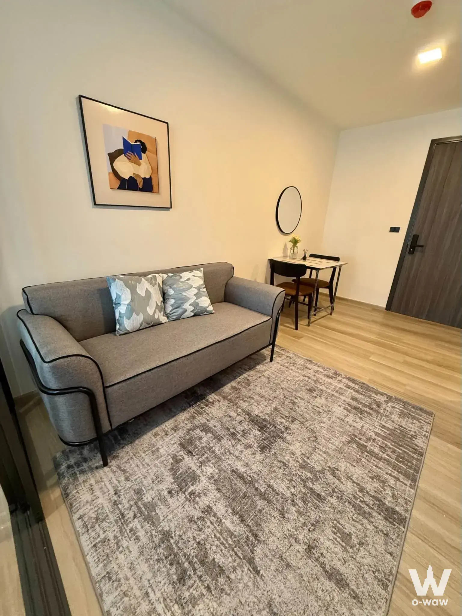 Living area in a Kaset condo with grey sofa and abstract wall art