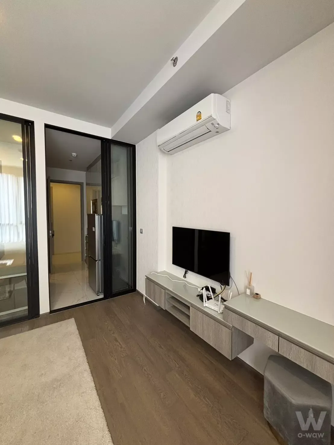 Living room in Park Origin Phaya Thai 1-bed condo with dark wood floors and a floating media console