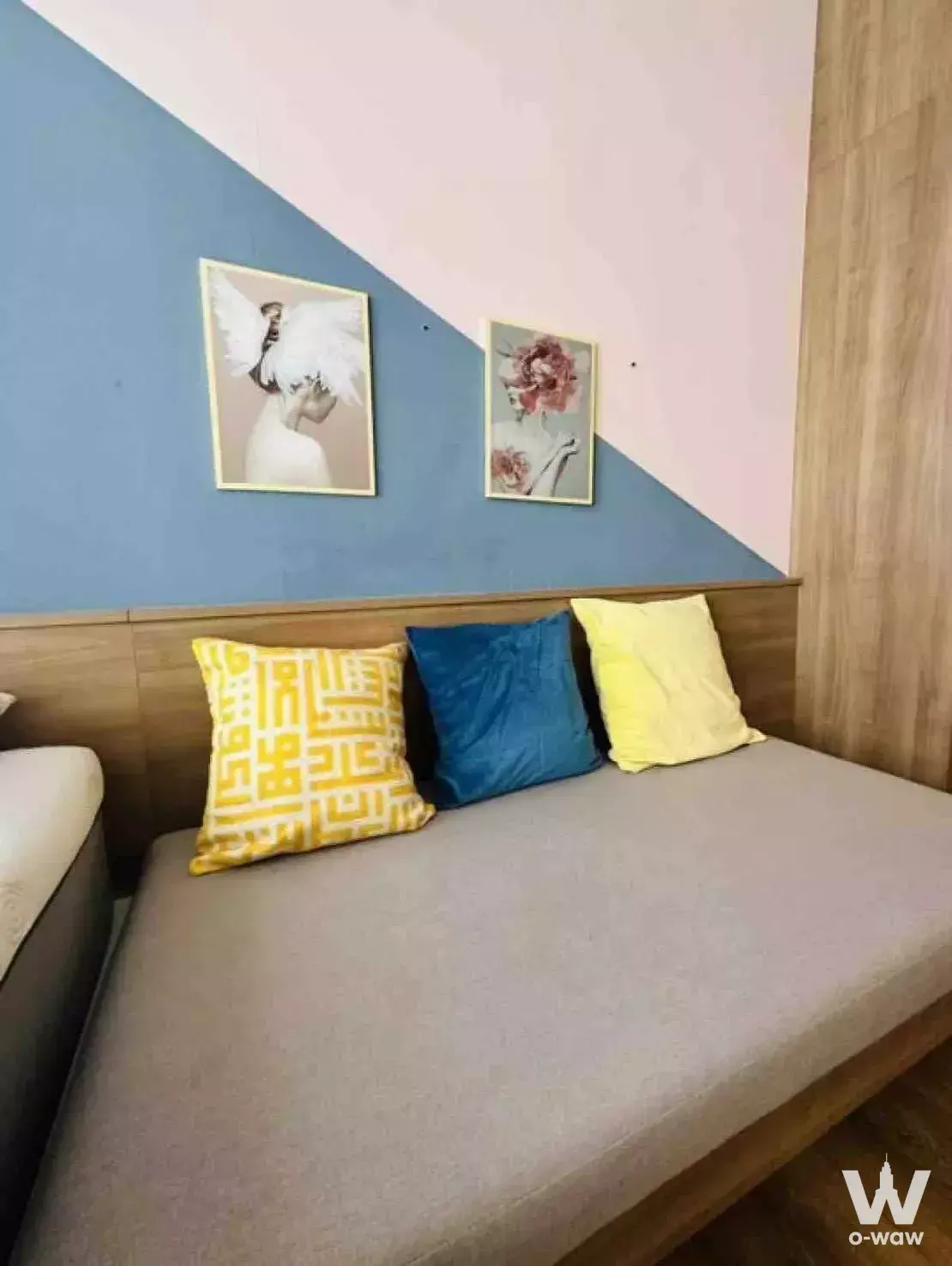 Bedroom corner in a 1-bed unit for rent at Park24 with a window seat, teal pillow, and two-tone wall