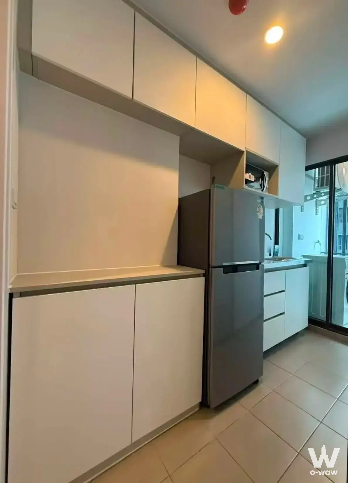 White kitchen cabinets and stainless fridge in a functional 1-bed condo for rent at Regent Home Wutthakat