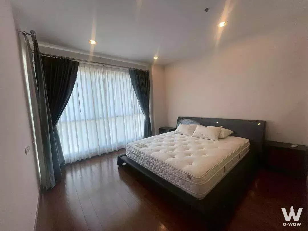 Queen bed with dark wood frame and sheer blinds in a 1-bed condo for rent at The Address Chidlom