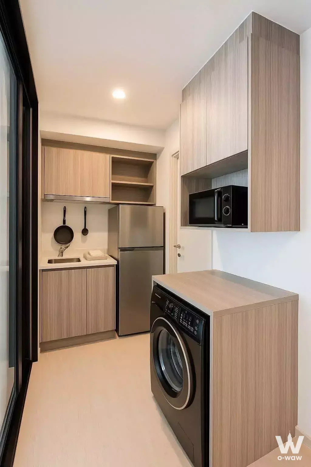 Compact kitchenette in a KnightsBridge Phaholyothin Interchange 2-bed condo with wood cabinets and laundry area